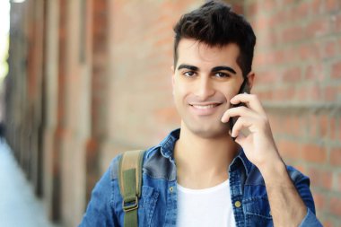 Sokakta telefonda konuşan genç latin adam portresi. Açık havada.