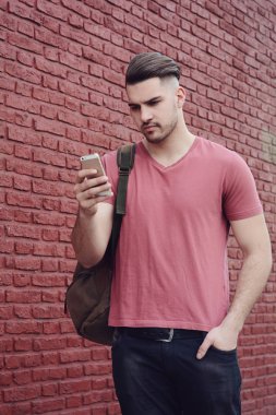 Telefonunda daktilo eden genç Latin adamın portresi. Açık havada..