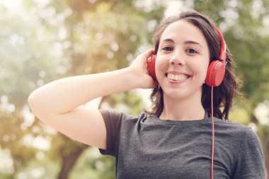 Kırmızı kulaklıklarla müzik dinleme genç güzel kadın portresi. Açık havada. Kentsel kavramı