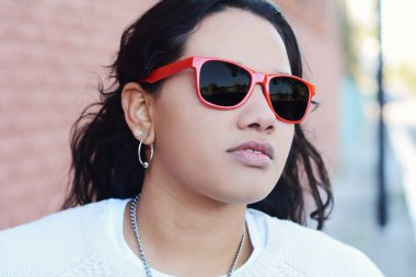 Genç latin kız kırmızı güneş gözlüğü portresi. Kentsel sahne. 