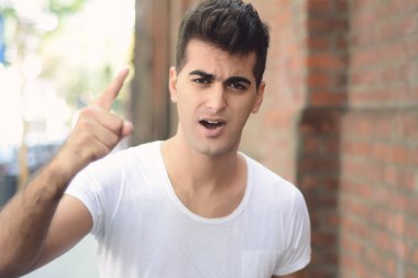 Genç latin adam kameraya bağırarak portresi. Açık havada