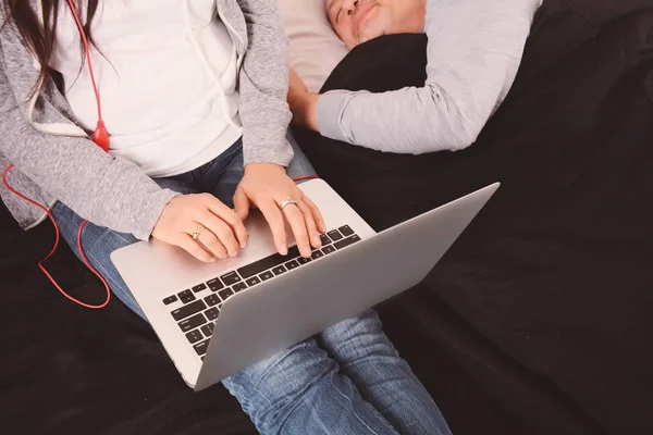 中年夫妇使用膝上型电脑和躺在床上 Ijndoors — 图库照片