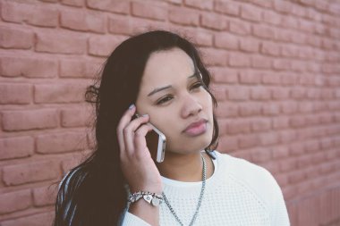 Genç latin kadın cep telefonu üzerinde söz portresi. Açık havada.