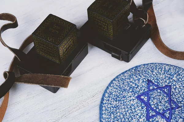 白い木製の背景に青いキッパーと黒のストラップと Tefilim のペア ユダヤ人のライフ スタイルのコンセプト — ストック写真
