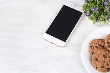 Boş ekran kol ve Çerezler ile mobil üstten görünüm Beyaz ahşap zemin üzerinde