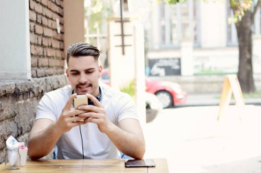 Telefonunda daktilo eden genç Latin adamın portresi. Açık havada..