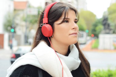 Kırmızı kulaklıklarla müzik dinleme genç güzel kadın portresi. Açık havada. Kentsel kavramı.