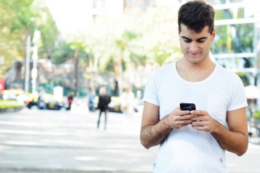 Holding kahve ve okuma iletisi yaptığı telefon genç adam. Açık havada.