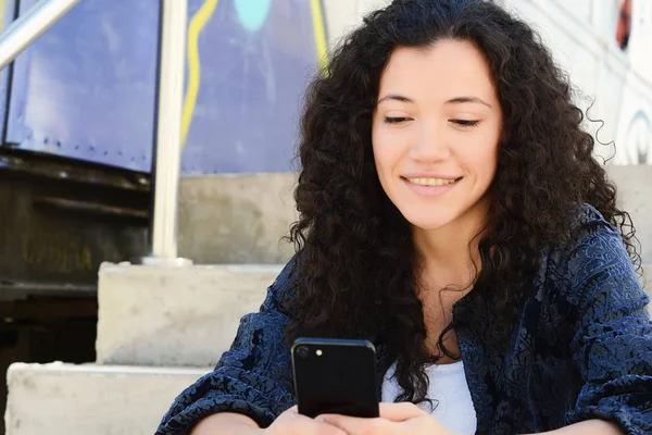 美丽的年轻妇女发送信息与智能手机在街上 — 图库照片
