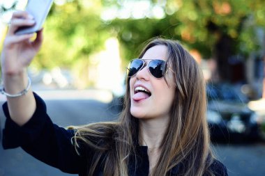 Selfie onun smartphone ile alarak güzel genç bir kadın portresi. Açık havada.