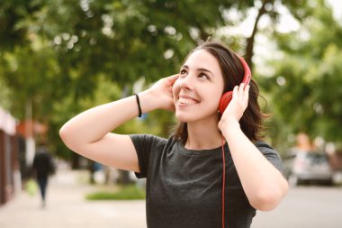 Kırmızı kulaklıklarla müzik dinleme genç güzel kadın portresi. Açık havada. Kentsel kavramı.