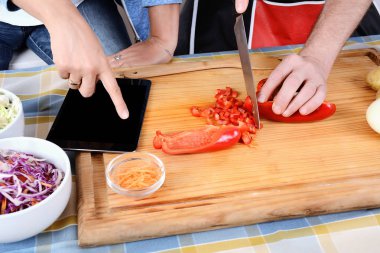 Çift dijital tablet kullanma ve evde mutfak gülümseyen yemek. İlişki kavramı