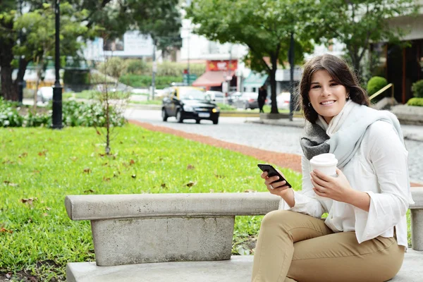 Portrait of beautiful woman holding paper coffee cup in the street. Urban city scene. Outdoors