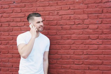 Sokakta telefonda konuşan genç latin adam portresi. Açık havada.