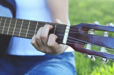 Akustik gitar parkta oynayan genç kadın closeup eller.