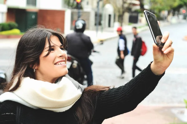 Selfie onun smartphone ile alarak güzel genç bir kadın portresi. Açık havada.