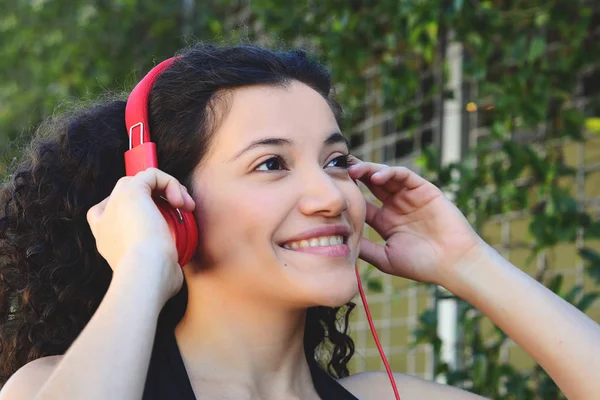 夏の公園で音楽を聴くヘッドフォンで若いラテン女性の肖像画 音楽を楽しむ — ストック写真