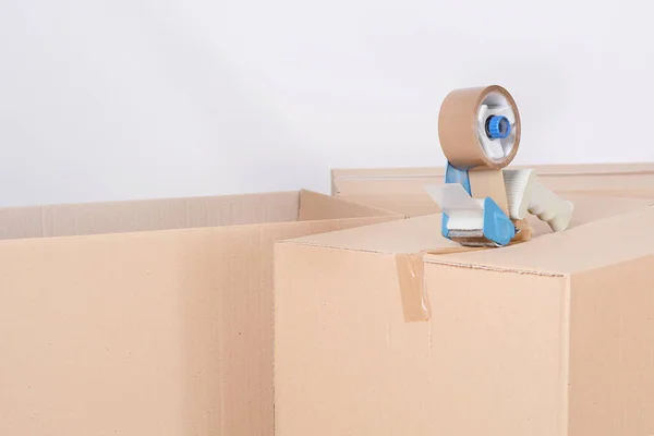 Tape dispenser sealing a shipping cardboard box. Indoors