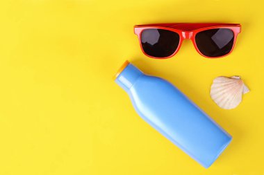Üstten görünüm güneş gözlüğü, kabukları, deniz yıldızı ve güneş kremi. Yaz konsepti. Açık mavi renkli 