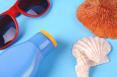 Üstten görünüm güneş gözlüğü, kabukları, deniz yıldızı ve güneş kremi. Yaz konsepti. Açık mavi renkli 