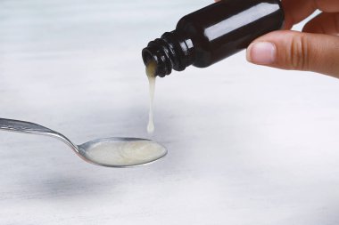 Öksürük şurubu içine kaşık dökme. Tıp kavramı. İzole beyaz arka plan