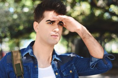 Çok uzaklara bakarak, bir şey ararken genç adam. Açık havada