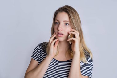 Studio telefonda konuşurken mutlu genç kadın portresi. Gri arka plan üzerinde izole