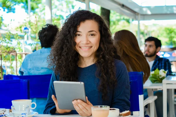 若いラテン女性のコーヒー ショップでデジタル タブレットを使用して — ストック写真