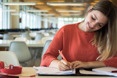 Üniversite kütüphanede çalışan genç kız öğrencinin portresi.