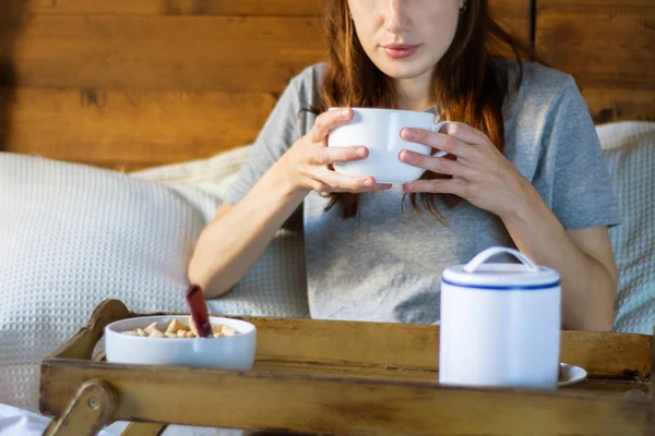 Young beautiful woman with a cup of coffee having breakfast on bed.