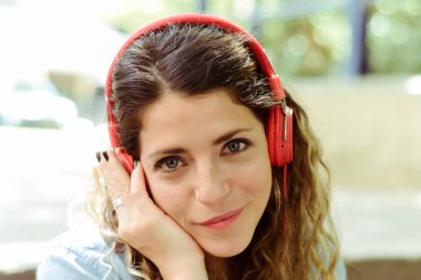 Mutlu genç kadın sokakta kulaklık ile müzik dinlemek. Yaz yaşam tarzı.