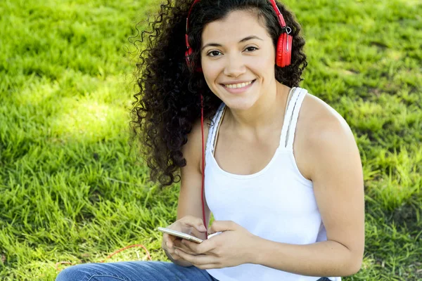 夏の公園で音楽を聴くヘッドフォンで若いラテン女性の肖像画 音楽を楽しむ — ストック写真