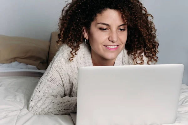 Молода жінка використовує свій ноутбук на ліжку — стокове фото