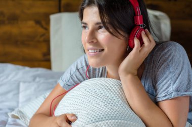 Genç kadın yatakta müzik keyfi.