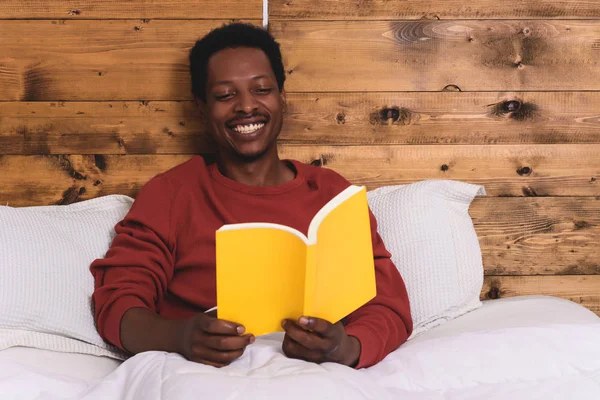 Hombre acostado en la cama y leyendo libro — Foto de Stock