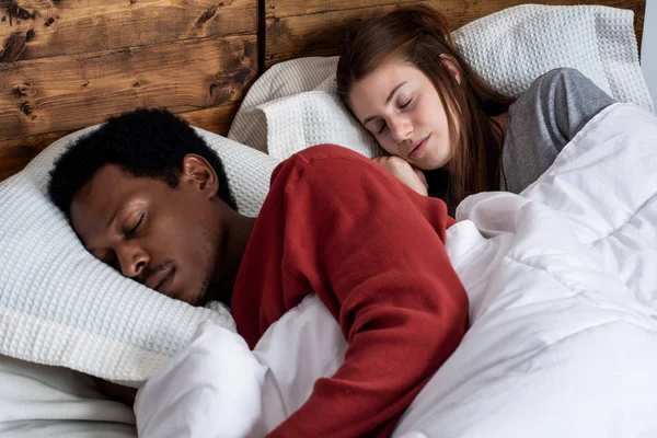 Jeune couple dormant dans un lit . — Photo