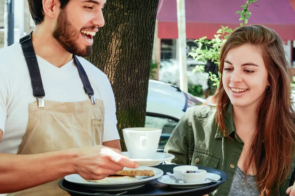 Junger Kellner serviert Kaffee an weibliche Kundin — Stockfoto