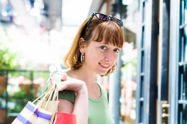 年轻的红发女子拿着购物袋在户外 — 图库照片
