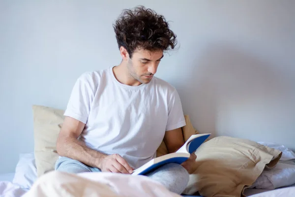 Człowiek czytając książkę w łóżku — Zdjęcie stockowe