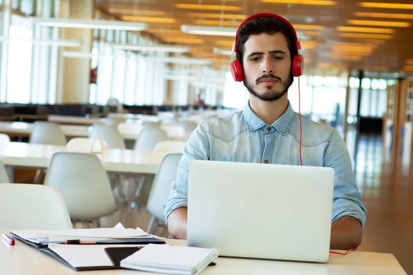 Joven estudiante masculino estudiando en la biblioteca . — Foto de Stock