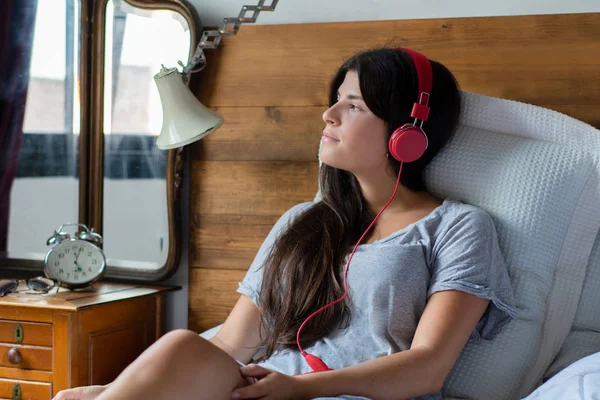 Młoda kobieta, słuchanie muzyki na łóżku. — Zdjęcie stockowe