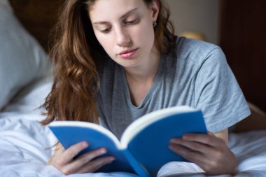 kadın yatakta döşeme ve kitap okuma