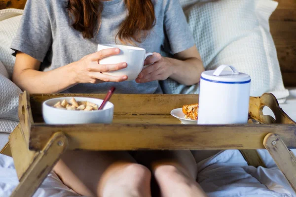 Jeune femme prenant le petit déjeuner au lit — Photo