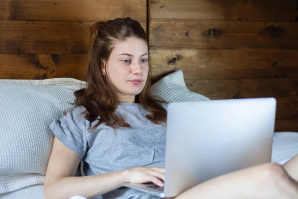 Giovane donna che utilizza il suo computer portatile sul letto — Foto Stock