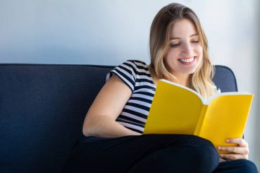 Evde kitap okuyan bir kadın.