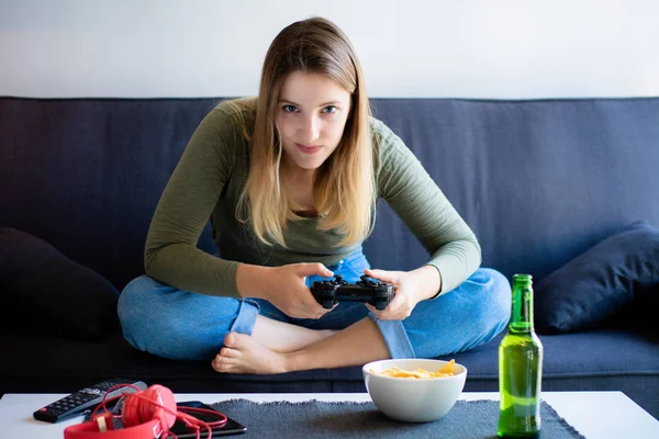 Young woman playing video games on sofa