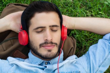 Genç adam rahatlatıcı ve çim müzik dinlerken.