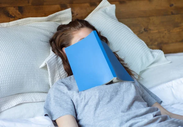 Mujer joven durmiendo en la cama con libro — Foto de Stock