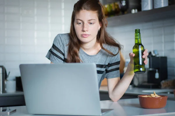 Giovane donna che utilizza laptop con cuffie in cucina — Foto Stock