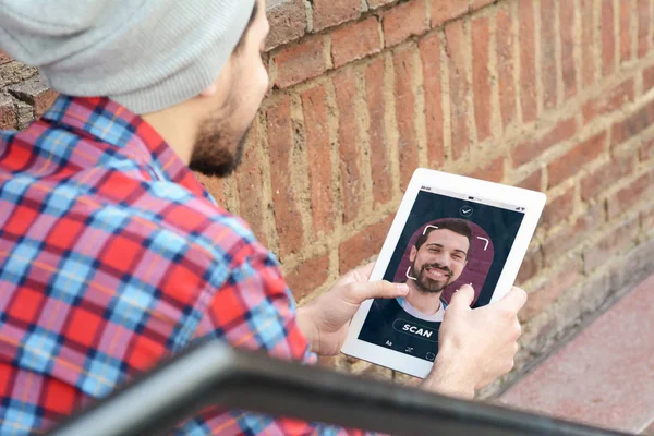 Young latin man unlocking smartphone with facial recognition tec